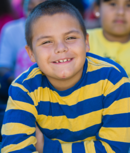 A young male student wearing striped shirt smiles at the camera.